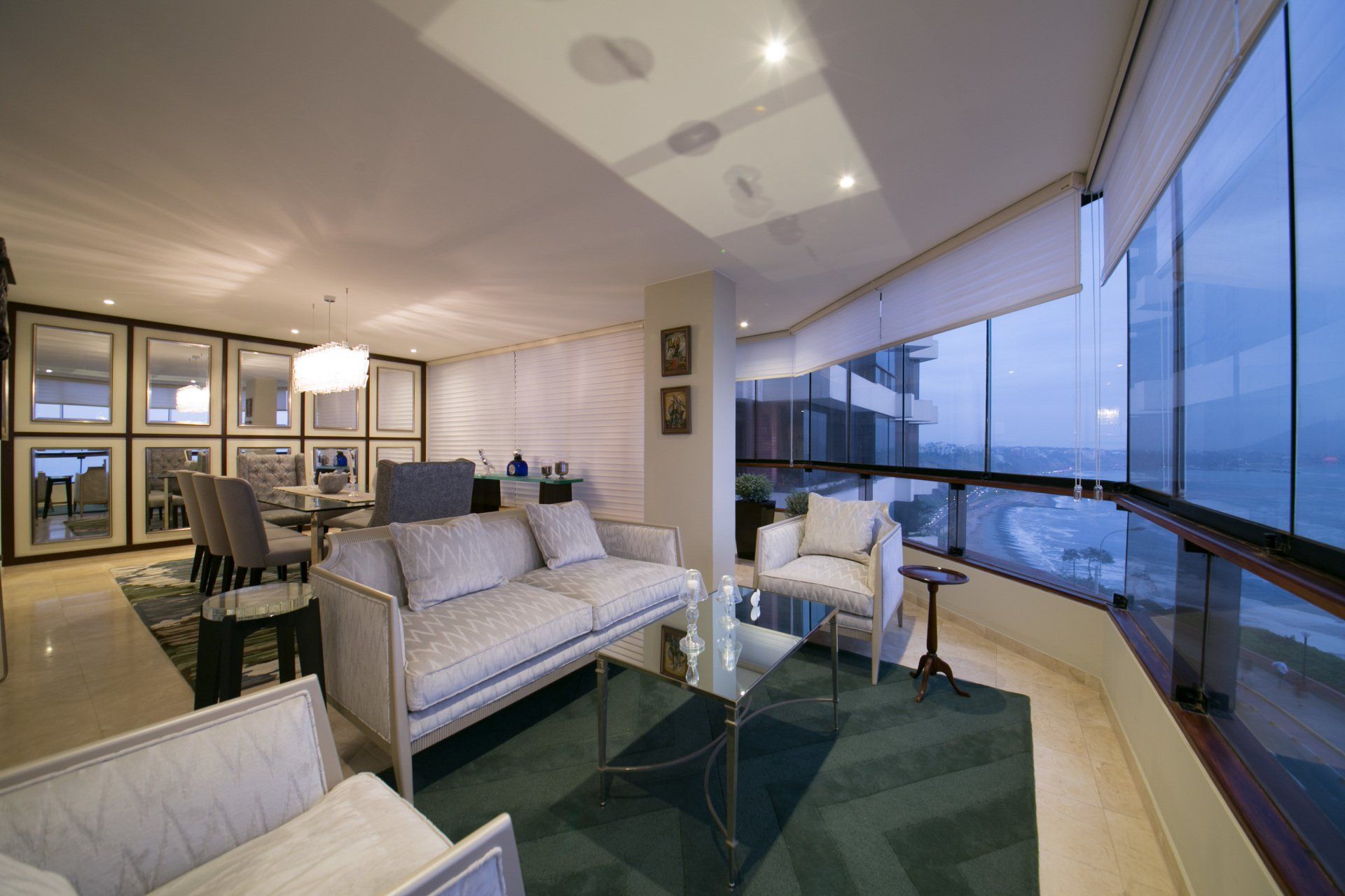 Una sala de estar con sofá y sillas y un balcón con vista al mar.