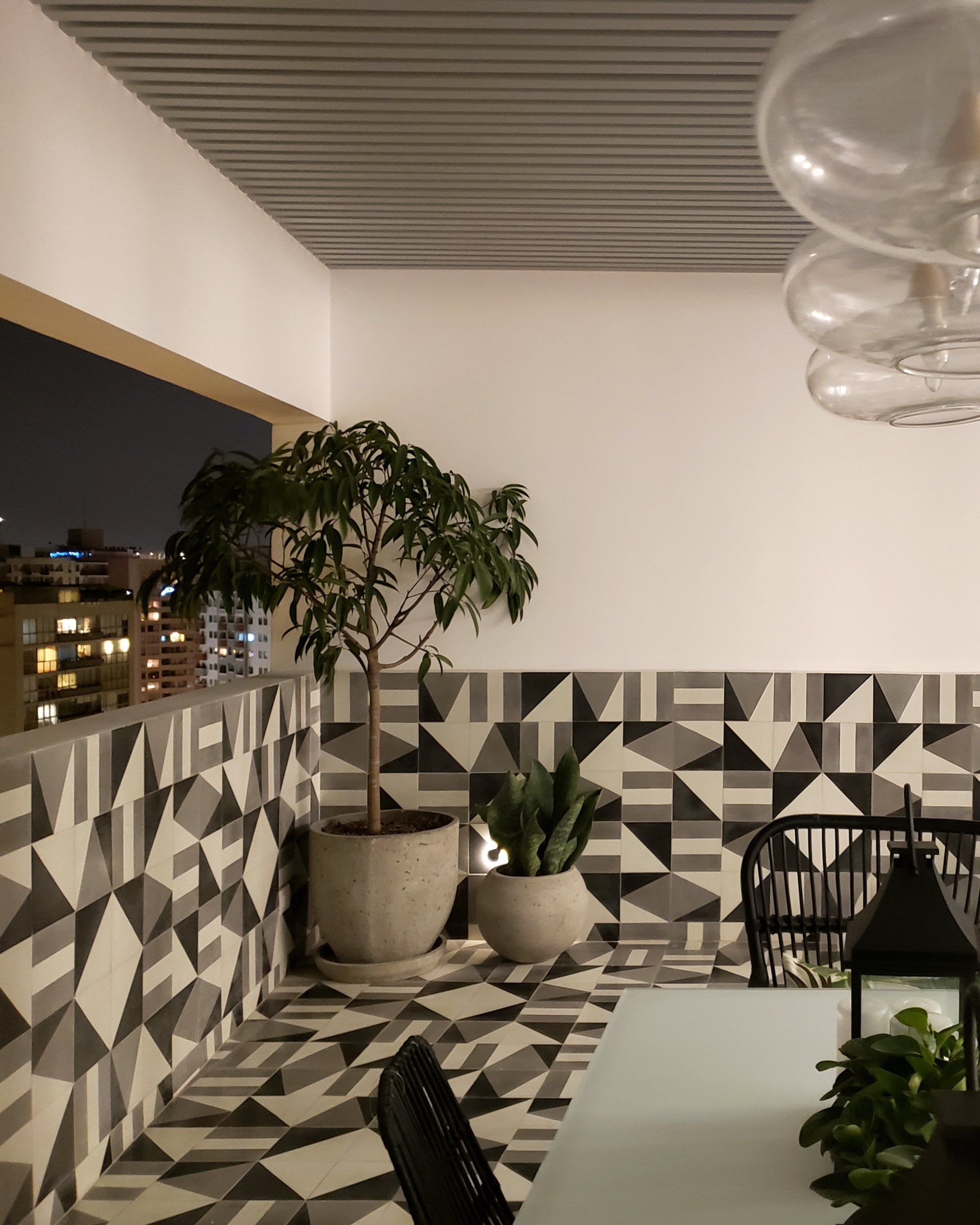 Un balcón con mesa y sillas y plantas en macetas.
