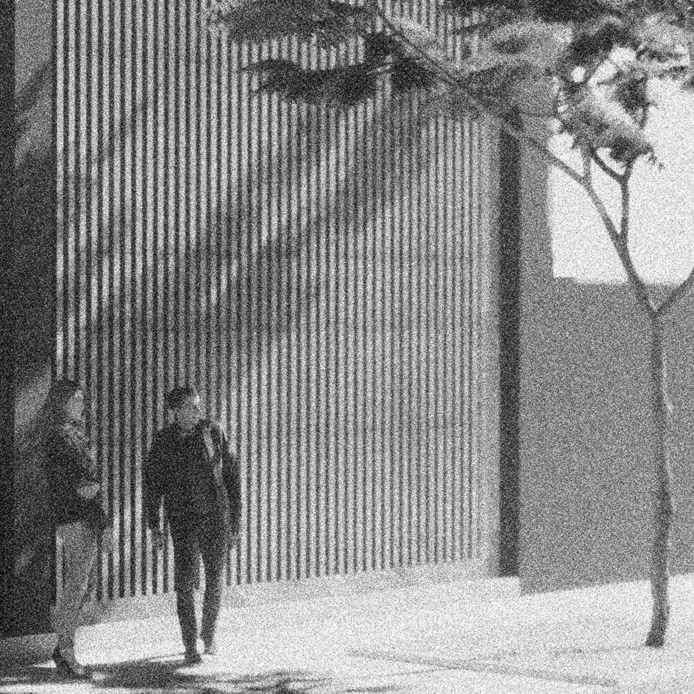 Una fotografía en blanco y negro de un hombre y una mujer caminando por una acera.