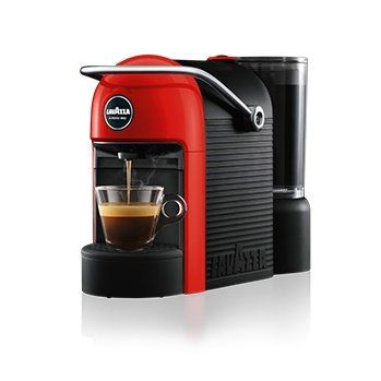 Una macchina da caffè Lavazza rossa e nera che prepara un espresso in una tazza di vetro, su sfondo bianco.