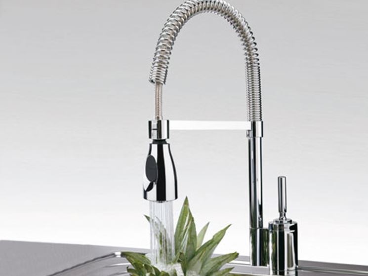 Un elegante rubinetto da cucina cromato con doccetta estraibile che sciacqua un ananas in una cucina moderna.