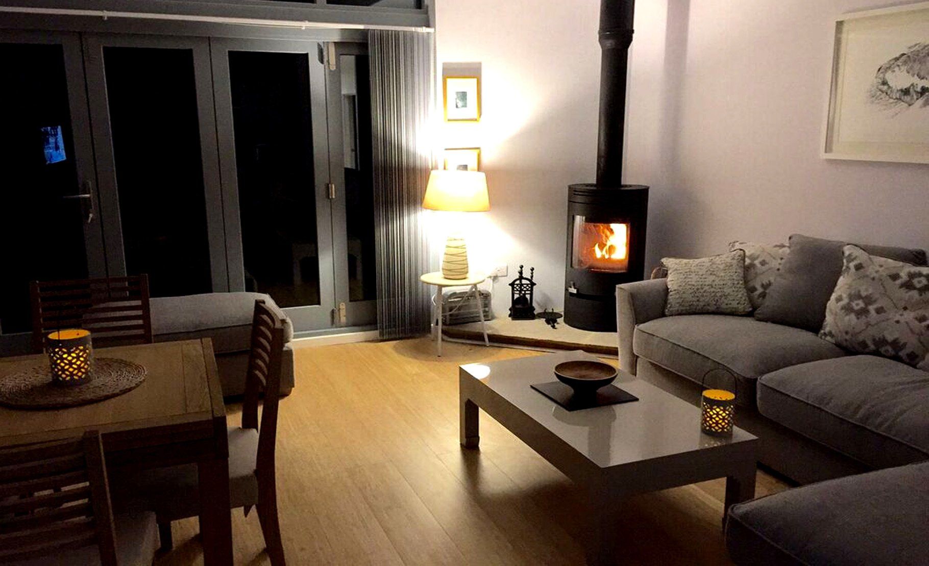 wood burner is lit and the lamps are on in this cosy interior