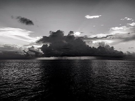 A black and white photo of a large body of water with clouds in the sky.