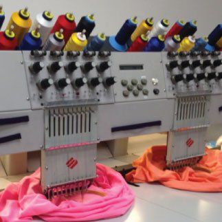 A row of embroidery machines are lined up in a room