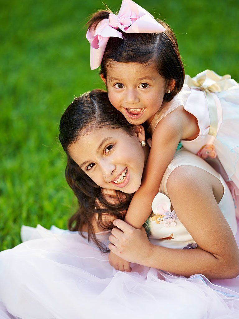 A little girl is sitting on another little girl 's back.