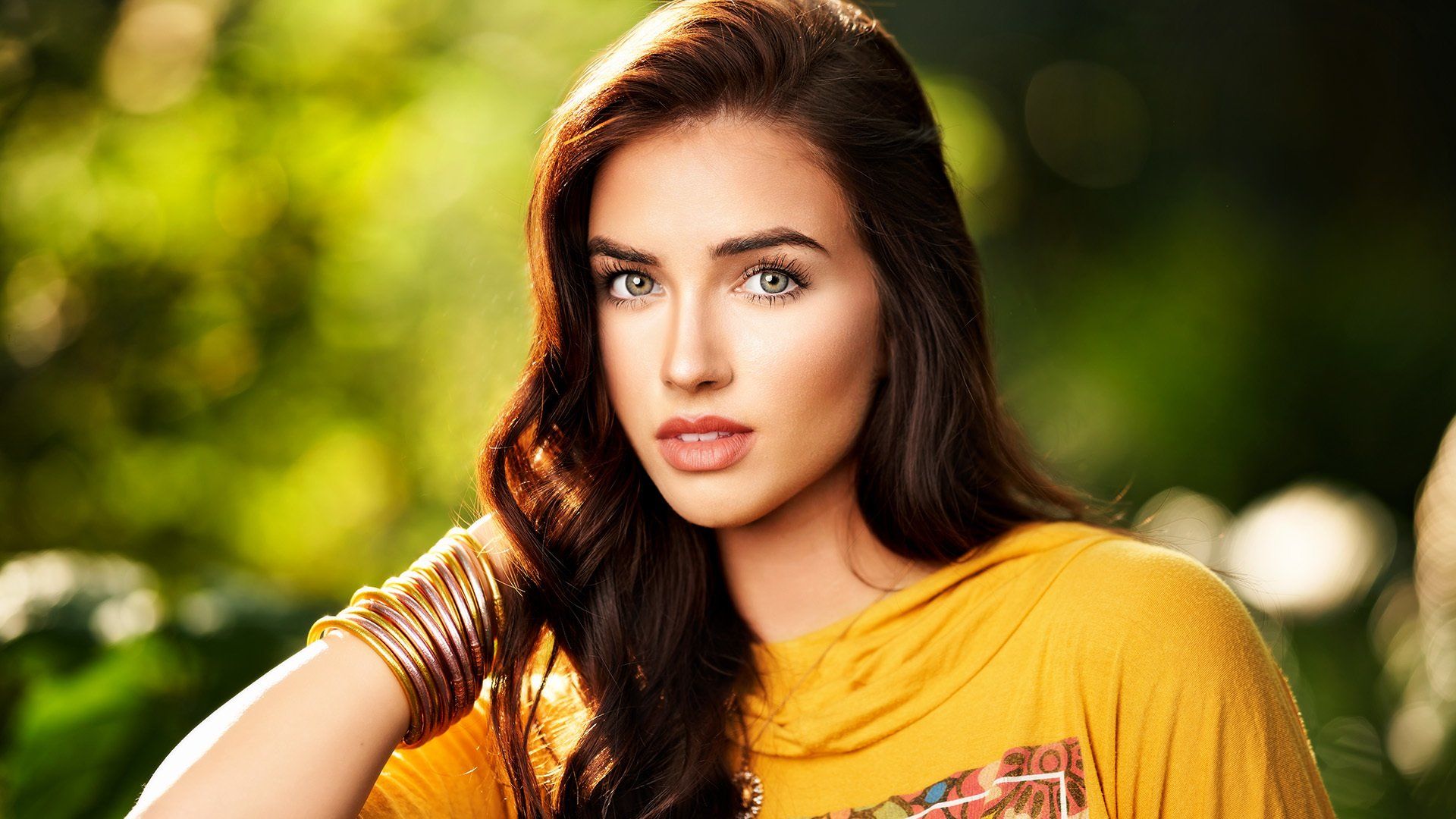 A close up of a woman wearing a yellow shirt and bracelets.