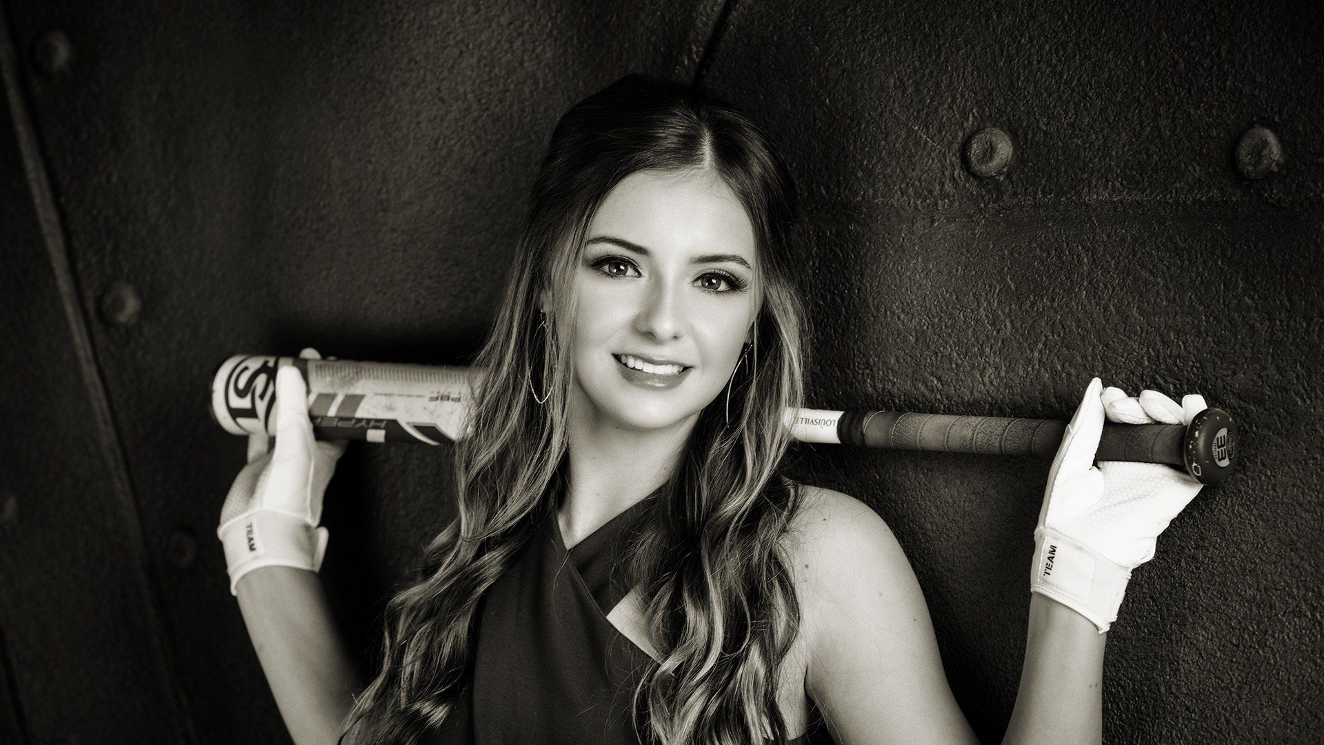 A black and white photo of a woman holding a baseball bat.