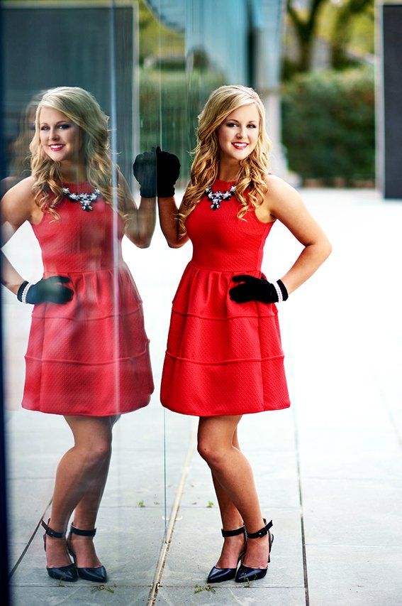 A woman in a red dress is standing in front of a mirror.