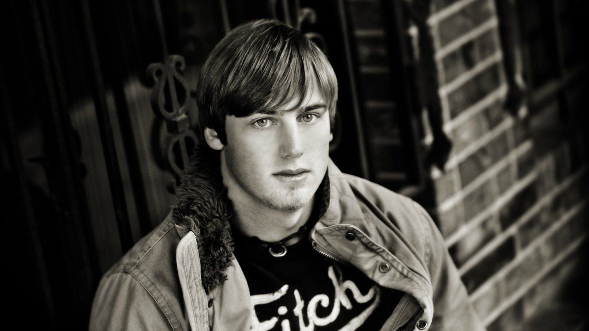 A black and white photo of a young man wearing a fitch shirt