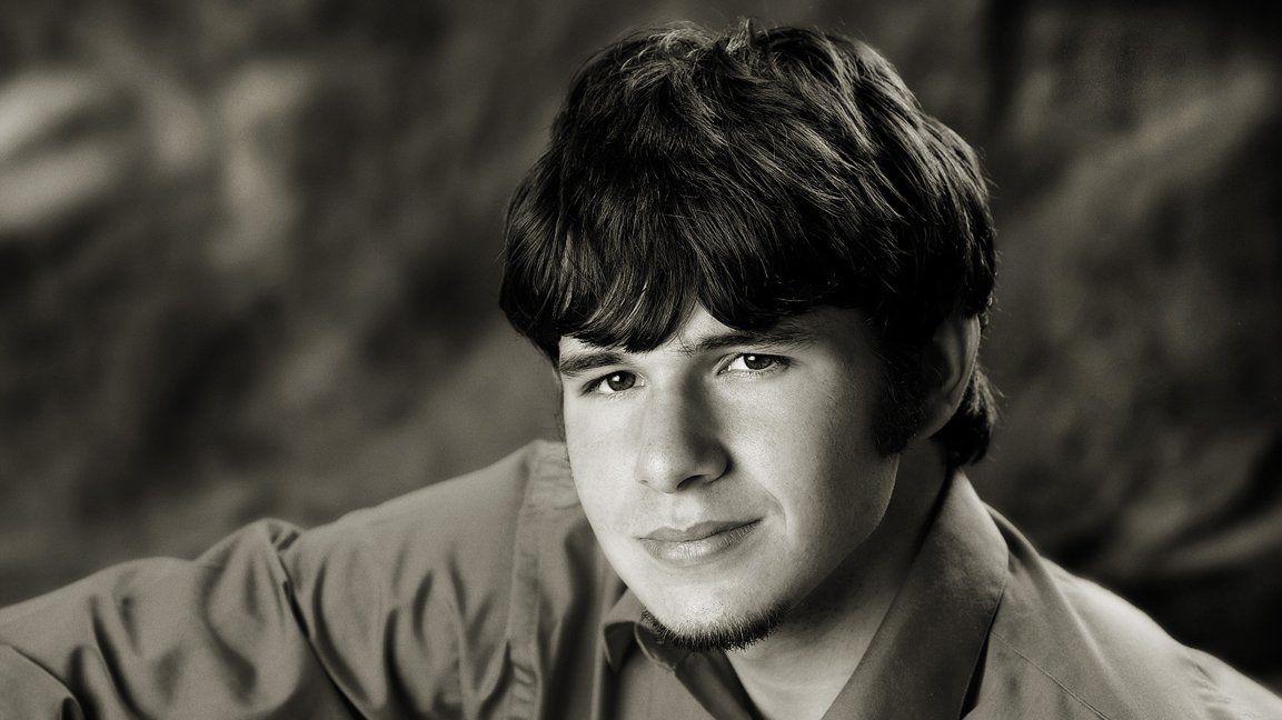 A black and white photo of a young man looking at the camera.