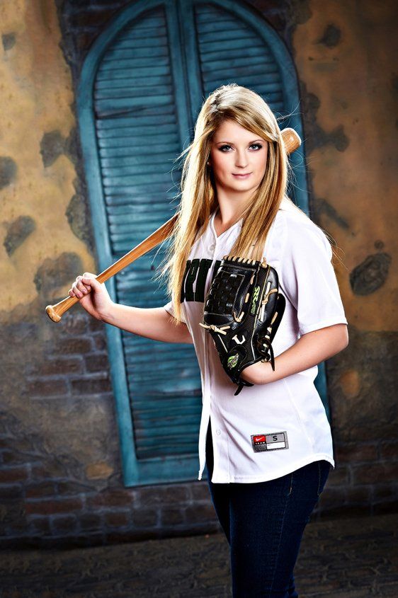 A woman in a baseball uniform is holding a bat and a glove.