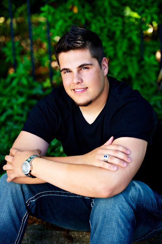 A young man in a black shirt is kneeling down with his arms crossed