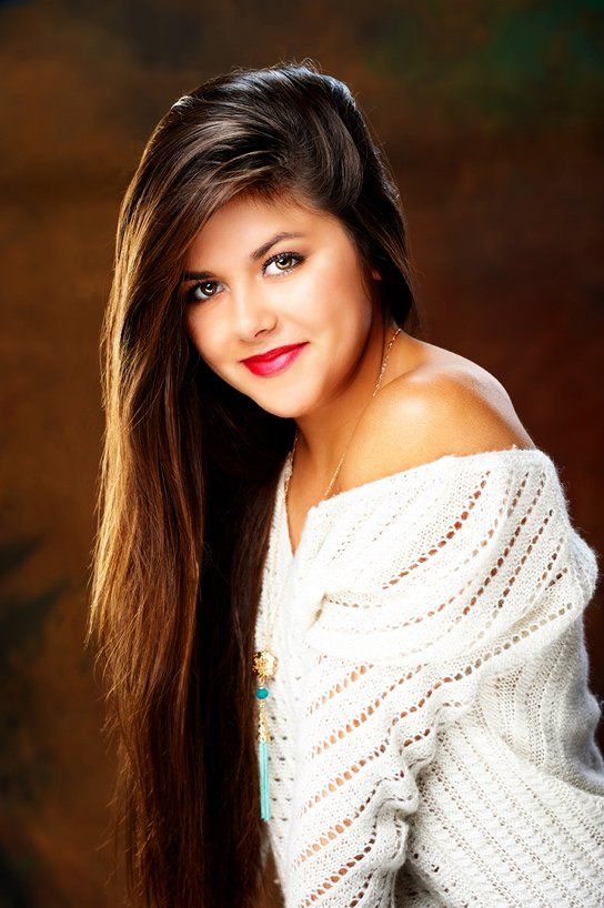 A woman with long hair is wearing a white sweater and red lipstick.