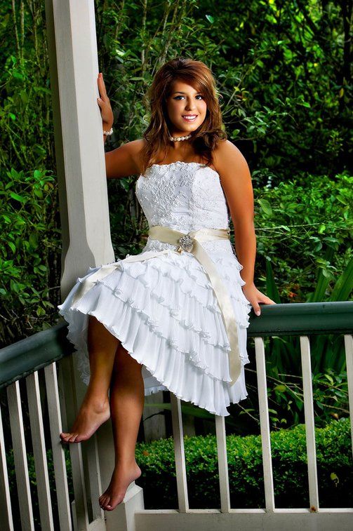 A woman in a white dress is sitting on a railing.