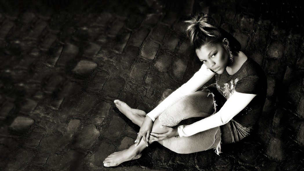 A black and white photo of a woman sitting on the ground