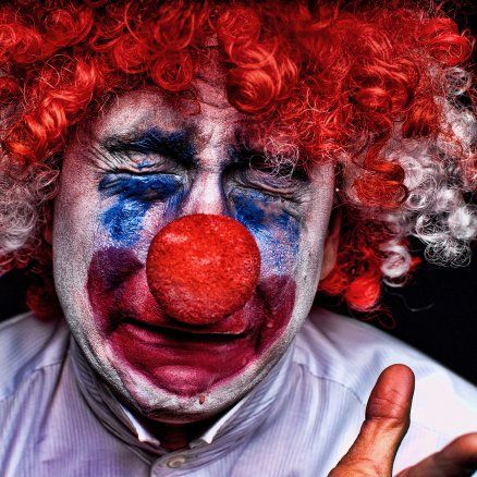 A man dressed as a clown with red hair and a red nose.