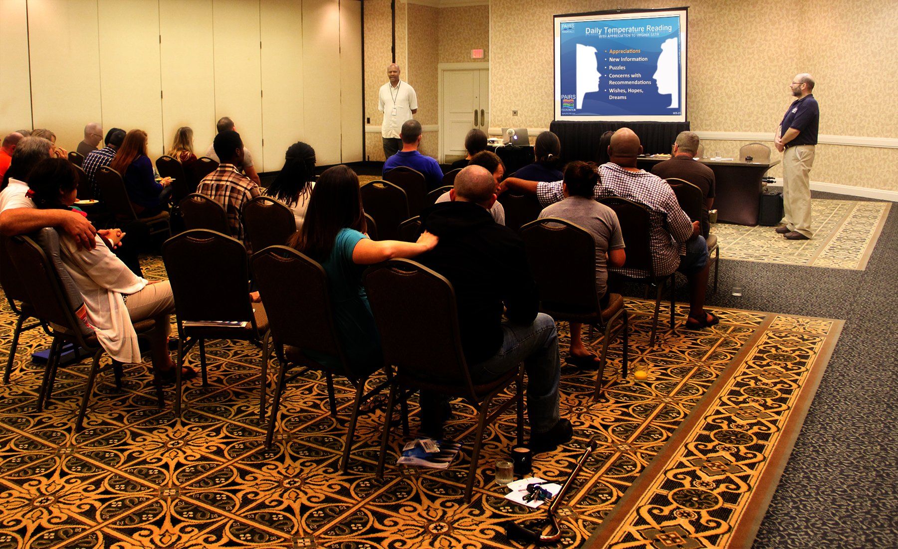 A group of people sitting in chairs watching a presentation