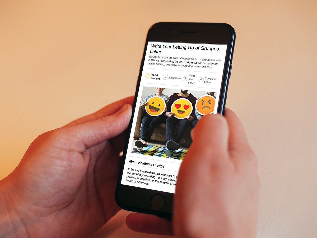 A person is holding a cell phone with emojis on the screen.