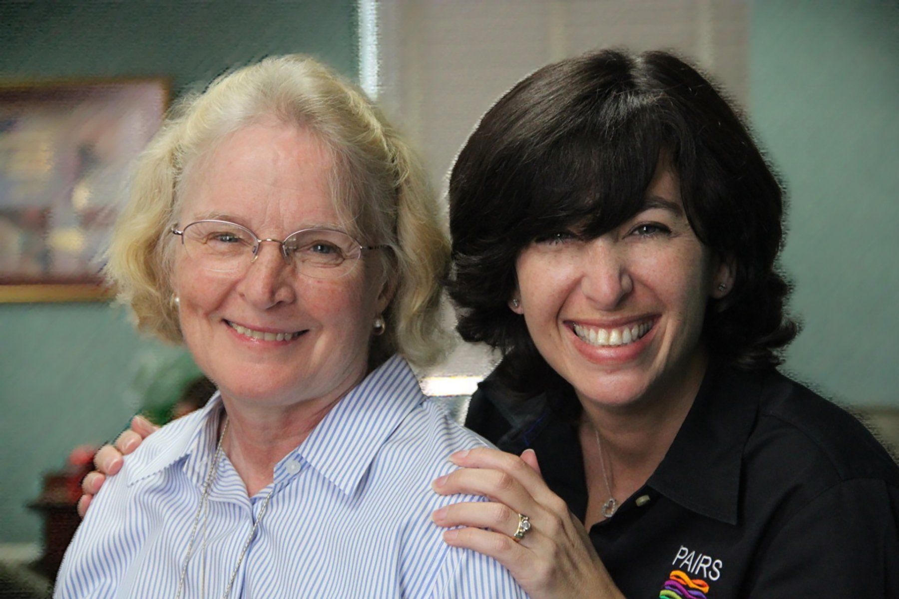 Two women are posing for a picture together and smiling for the camera.