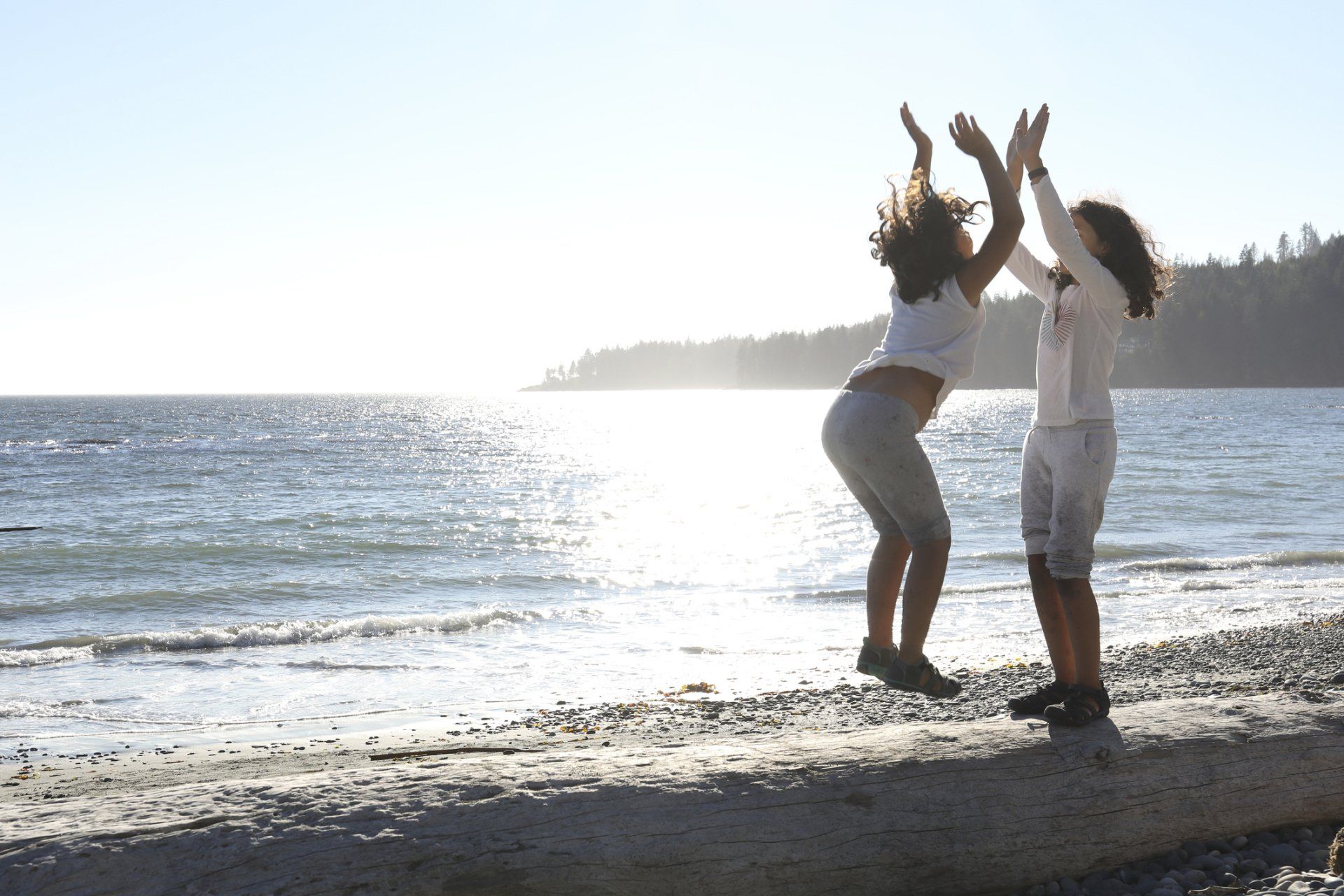 Two girls are jumping in the air on a beach