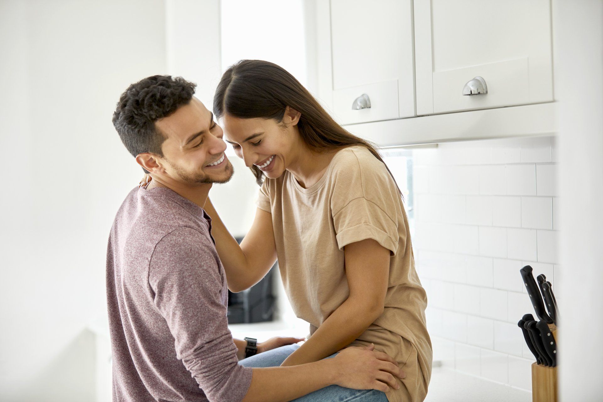 A man and a woman are hugging in a kitchen.
