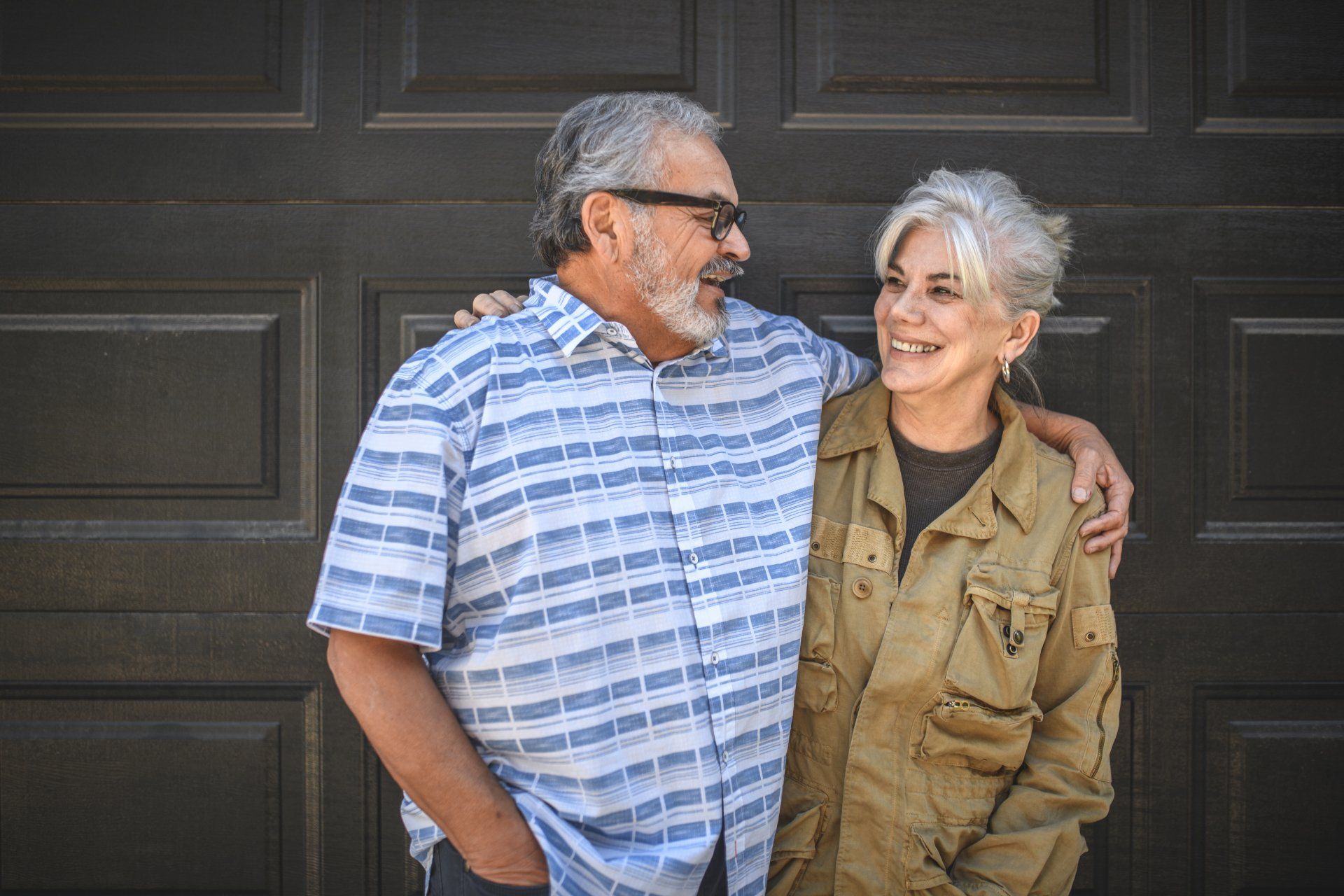 A man and a woman are standing next to each other in front of a garage door.