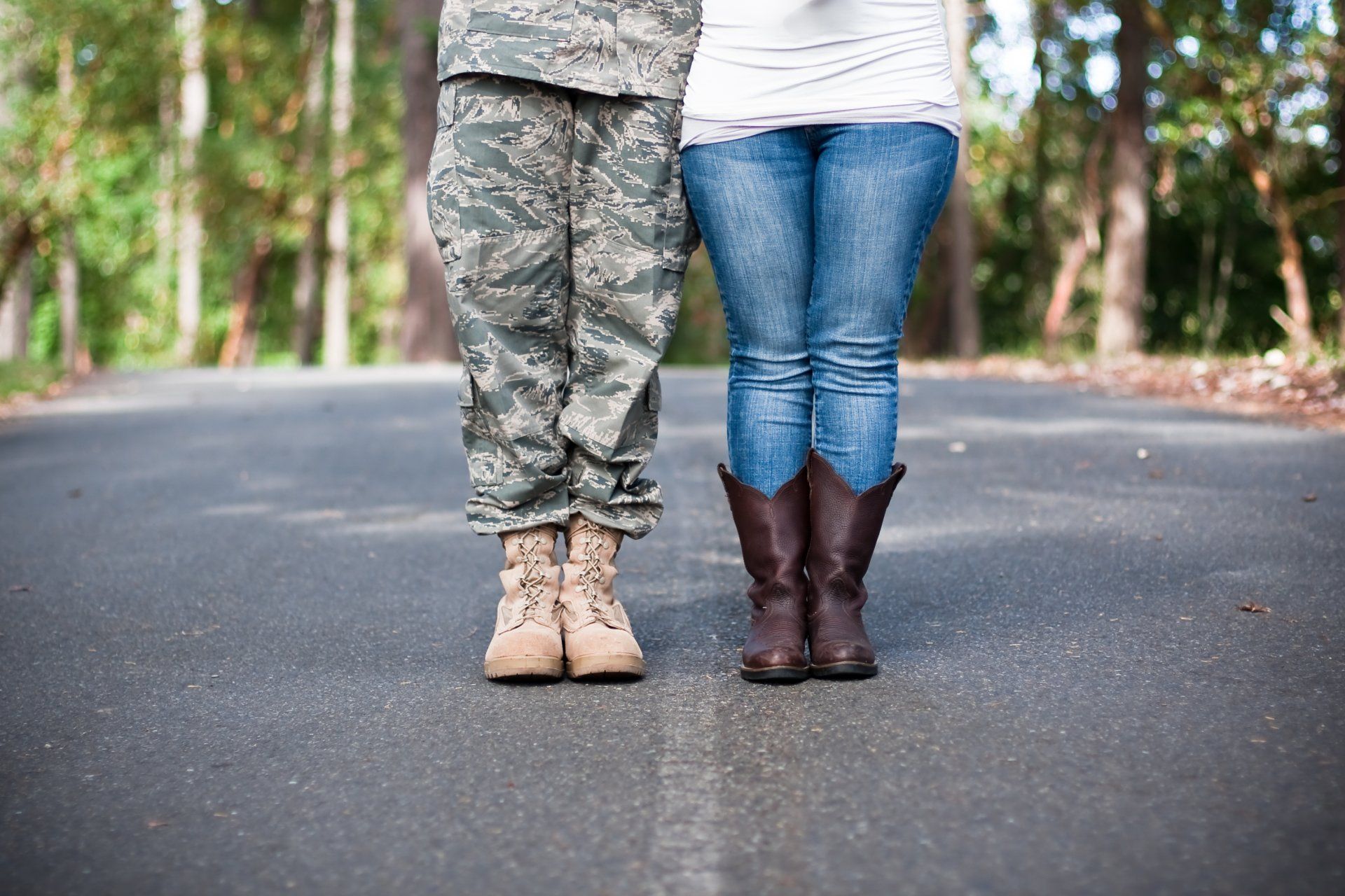 A soldier and a woman are standing next to each other on a road.