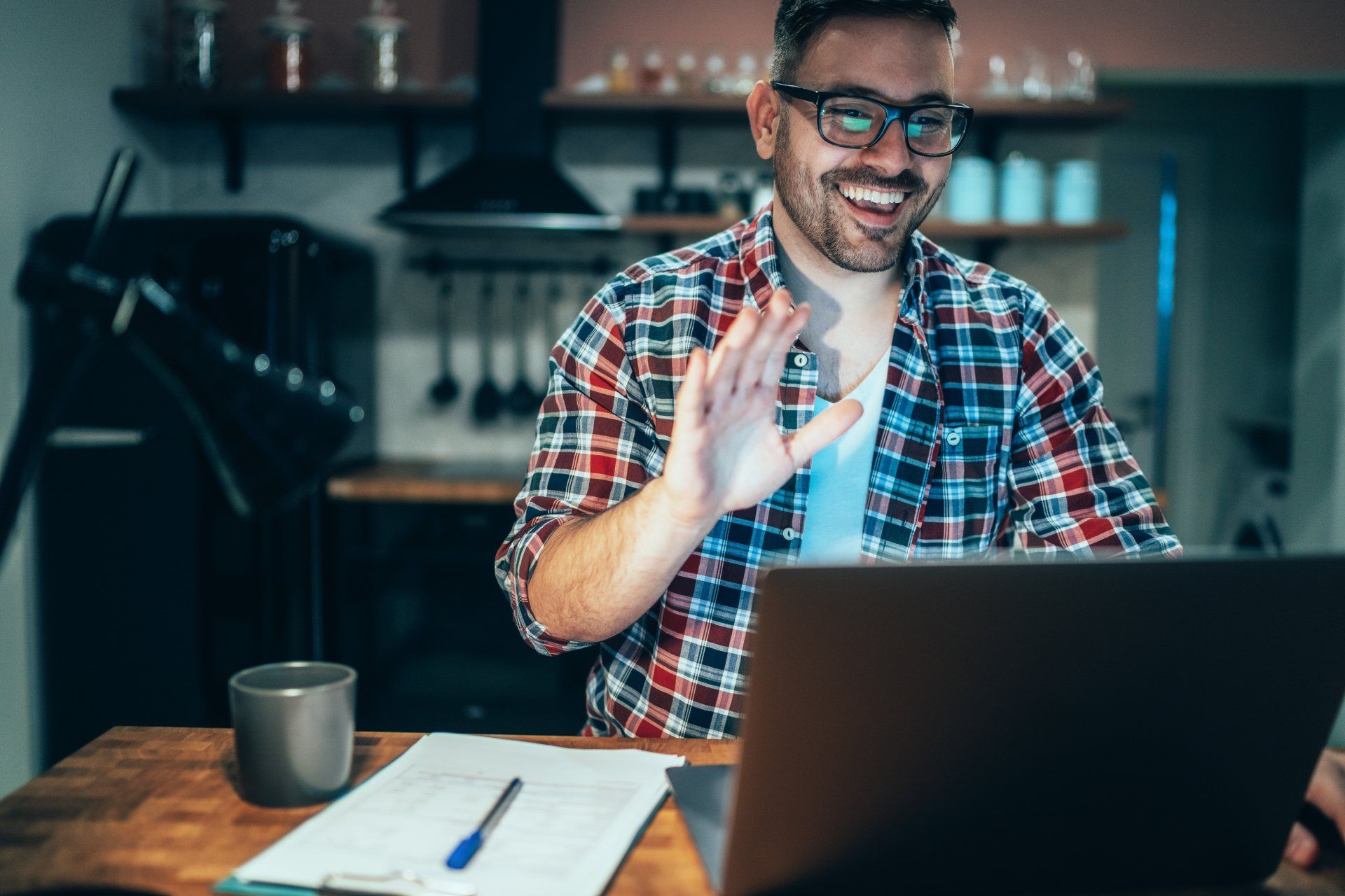 A man is sitting at a table using a laptop computer.