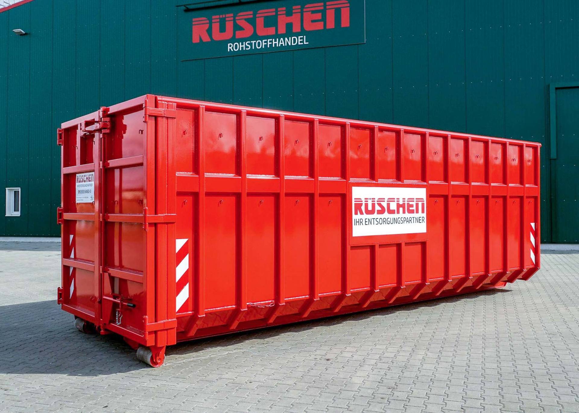 Rüschen Abrollcontainer Ein großer roter Abrollcontainer mit dem Wort „Rüschen“ darauf