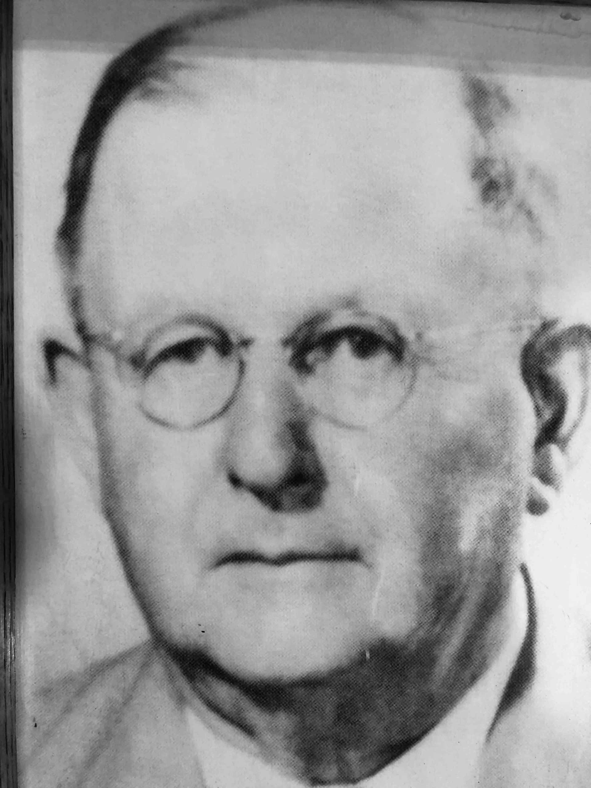 Black-and-white portrait of a person wearing round-rimmed glasses, shown from the chest up.