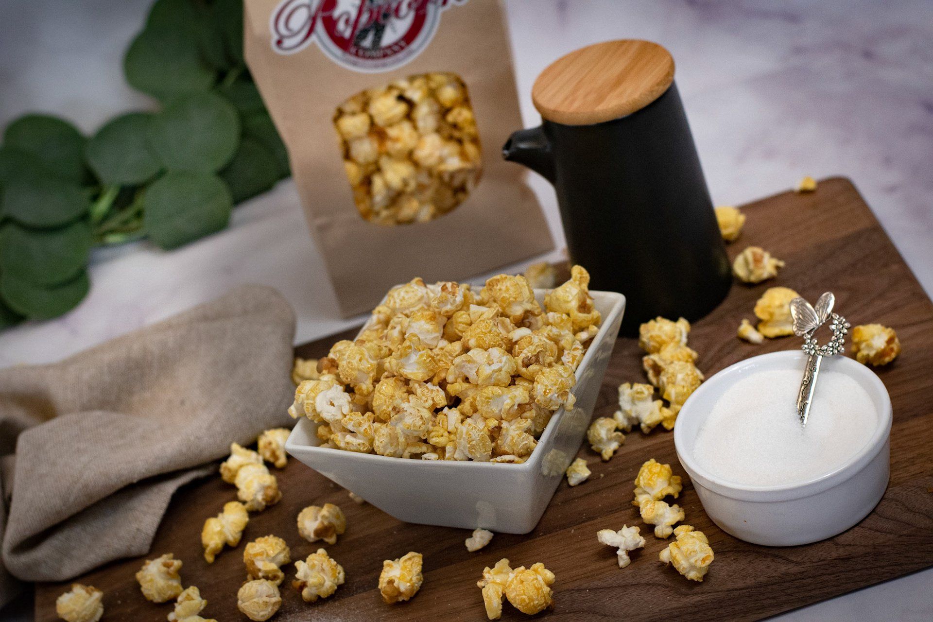 A bowl of caramel popcorn is sitting on a wooden cutting board.