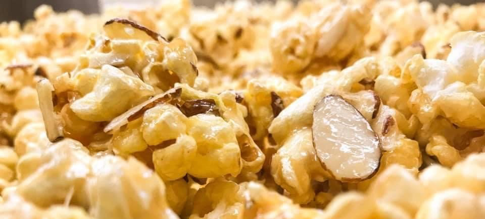 A close up of a pile of popcorn with almonds on top.