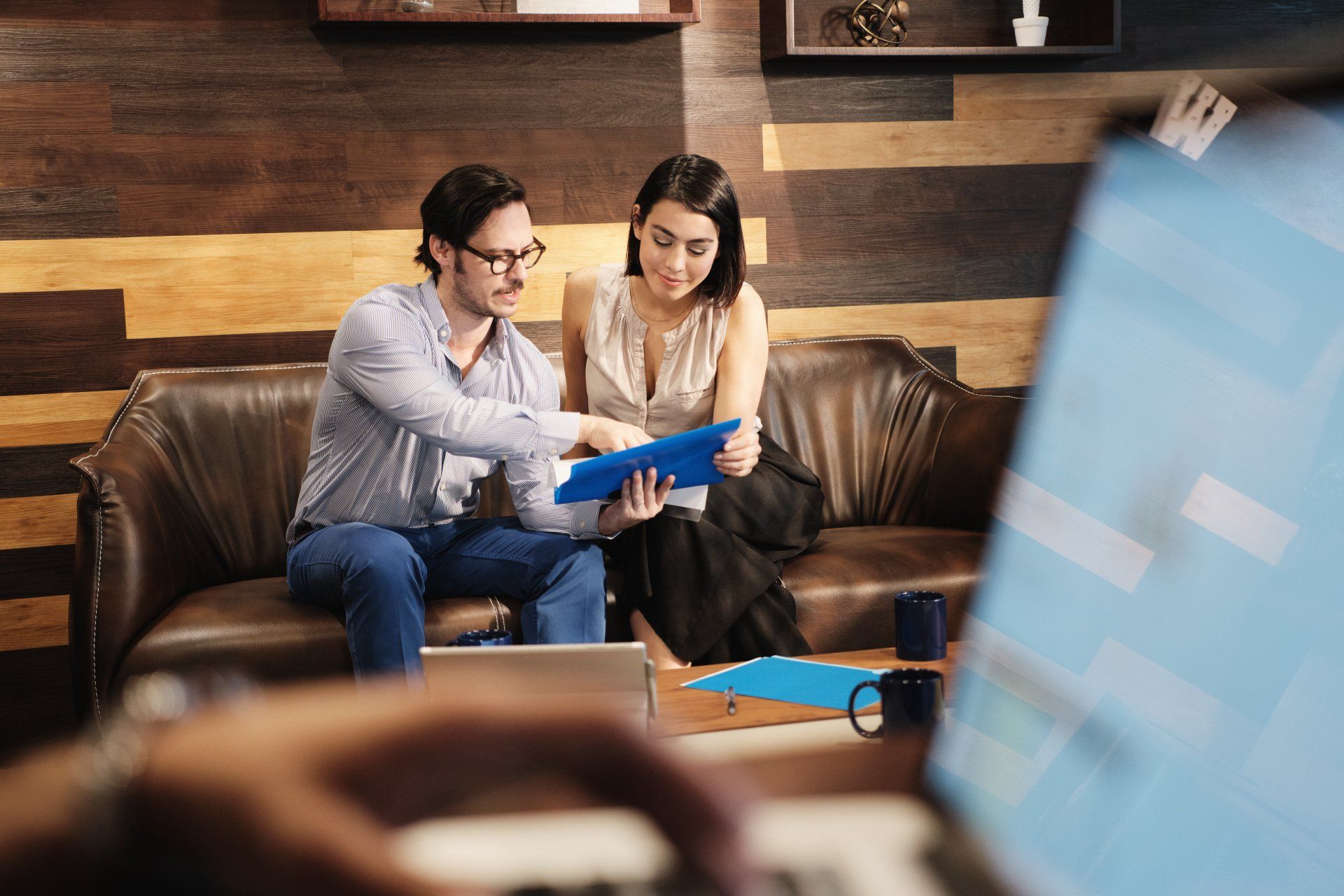 A business man and business woman look through a folder together.
