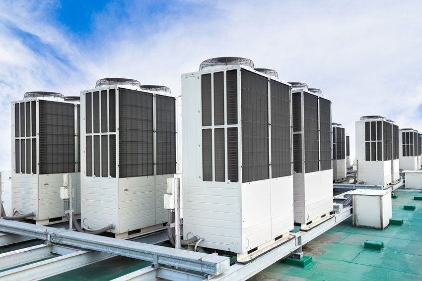 A row of air conditioning units on rooftop with blue sky