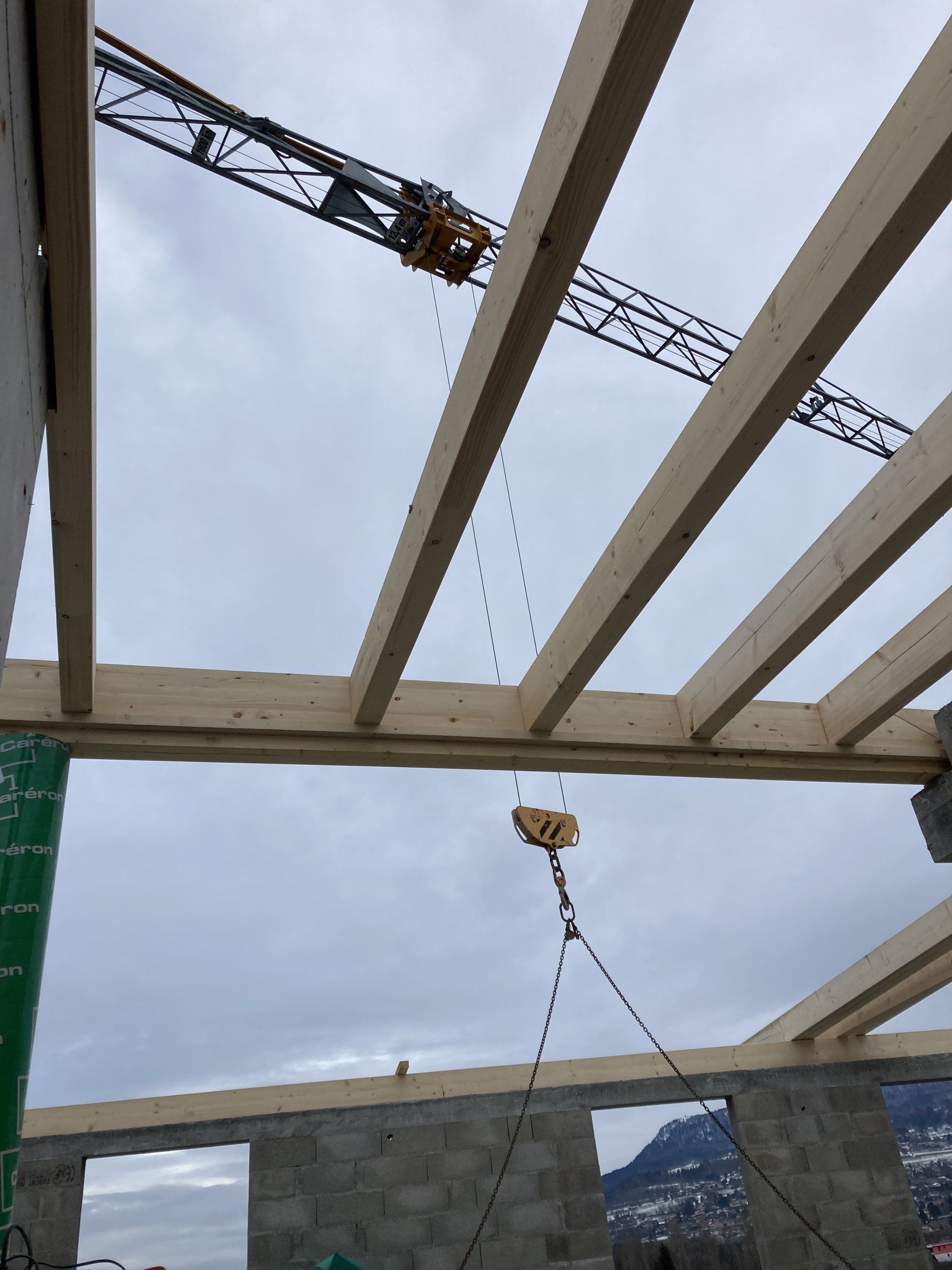 Une grue soulève une poutre en bois sur un chantier de construction