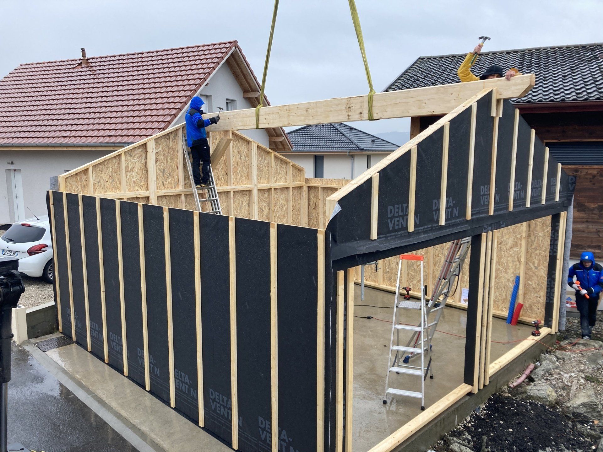 Un groupe de personnes travaille sur une structure en bois devant une maison.
