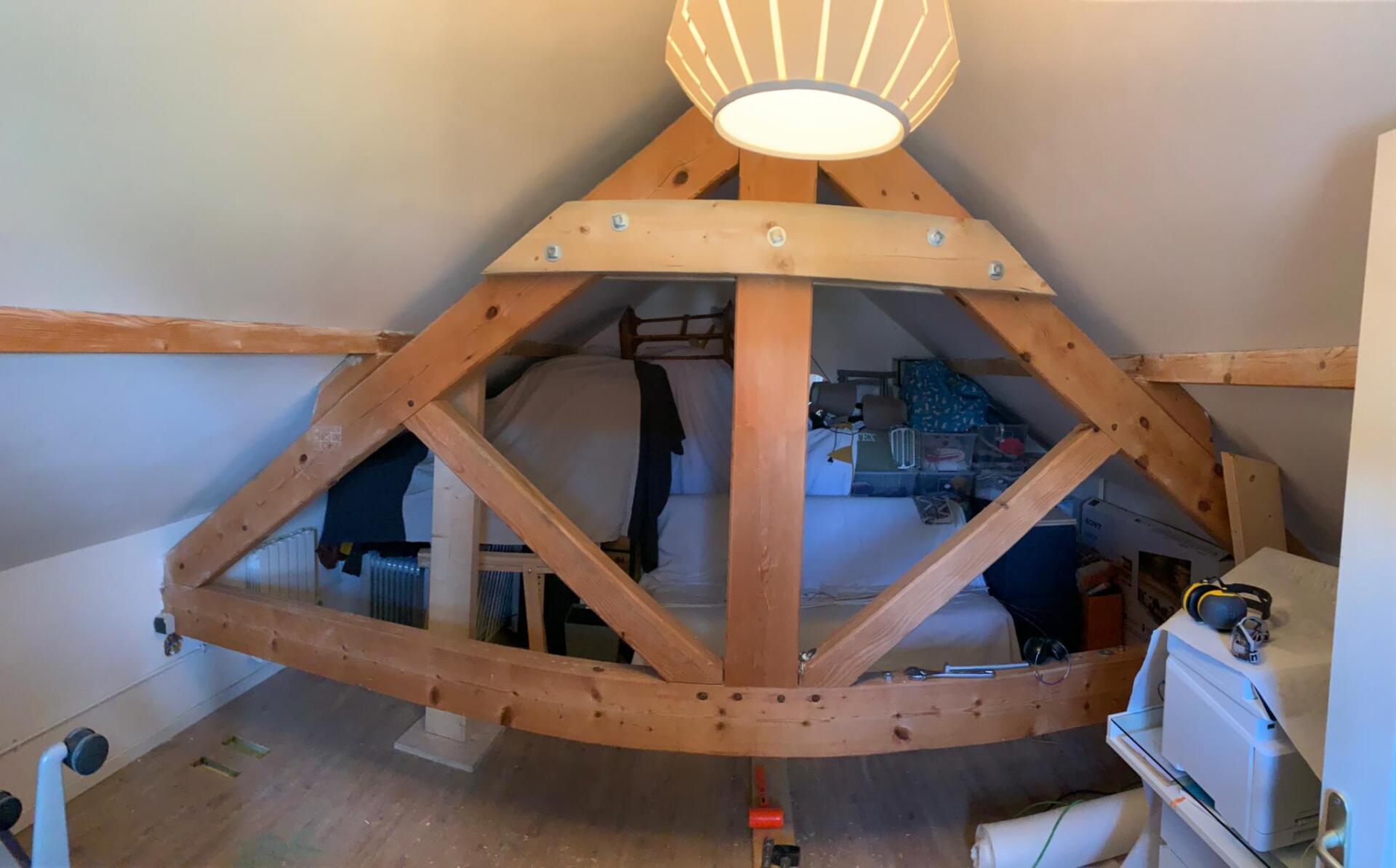 Il y a un lit dans le grenier avec une structure en bois.