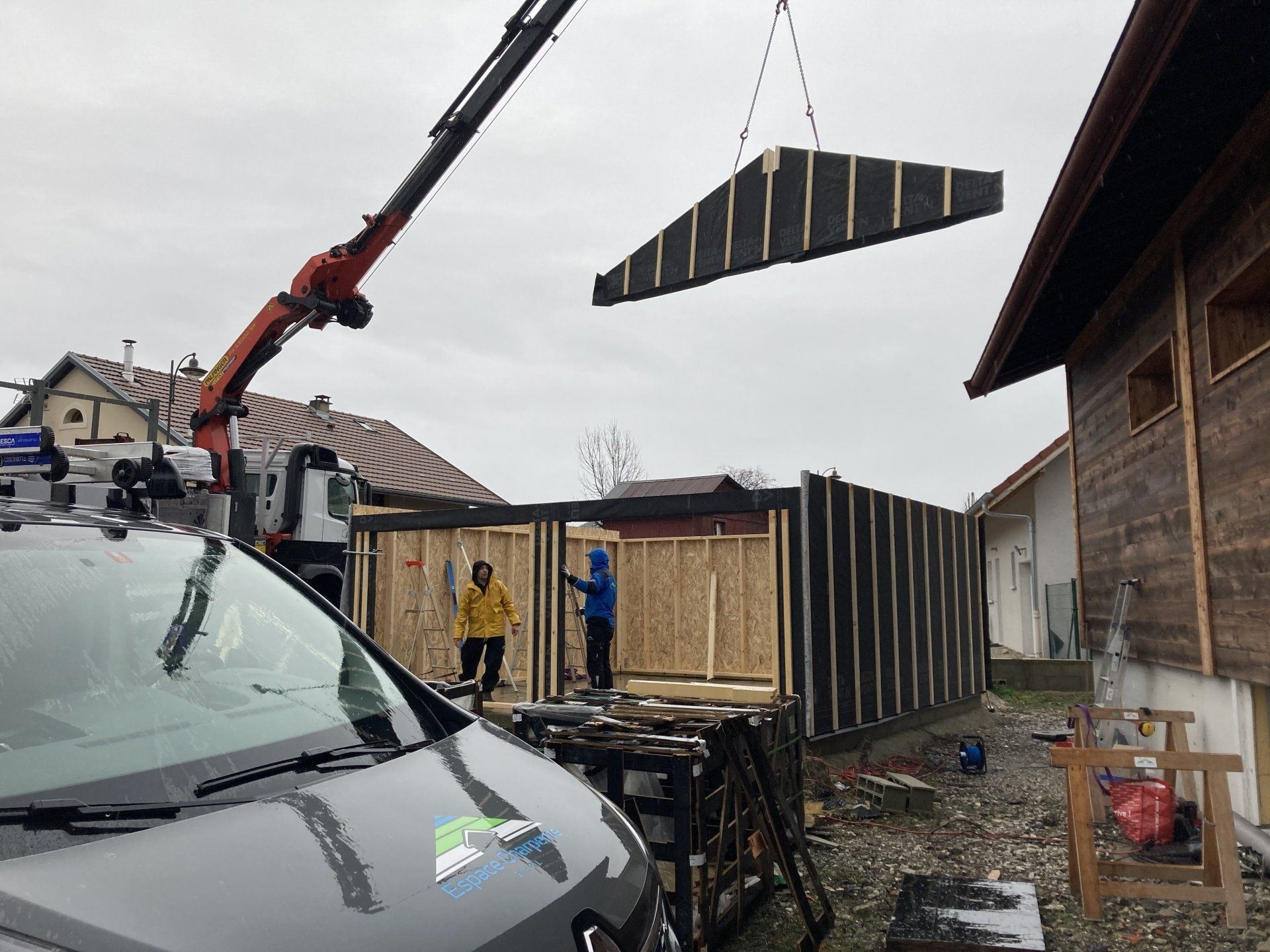 Une grue soulève un morceau de bois dans un bâtiment.