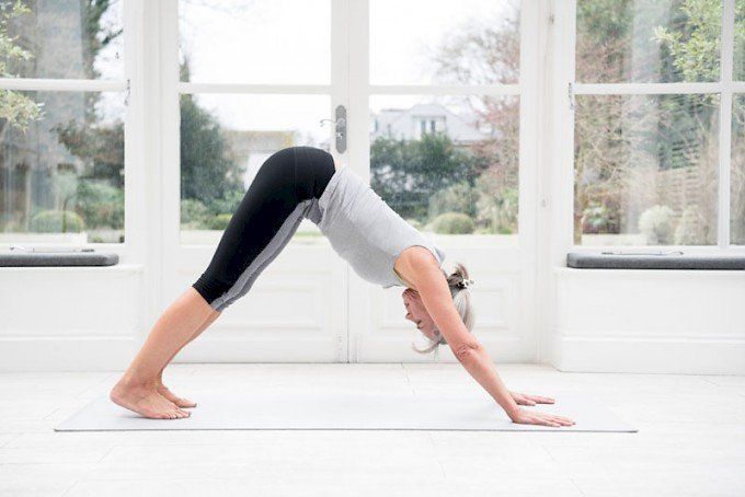A woman is doing a downward dog yoga pose on a yoga mat.
