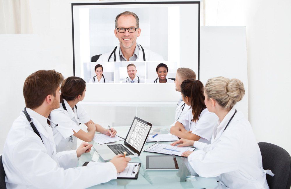 Team of doctors looking at projector screen in video conference meeting at hospital