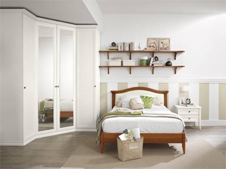 Camera da letto luminosa e minimalista con armadio bianco, letto in legno, mensole a muro e un piccolo comodino.
