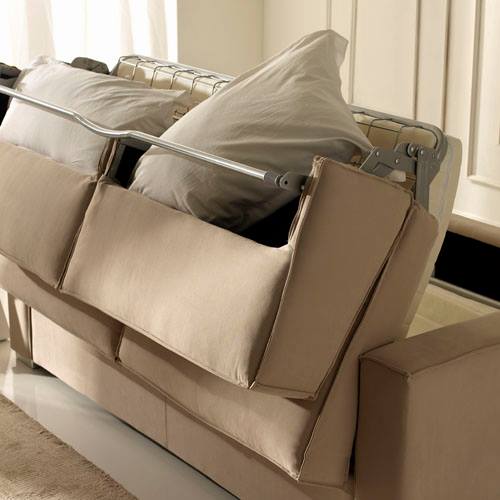 Un divano beige rovesciato su un fianco con cuscini grigi in un luminoso soggiorno.