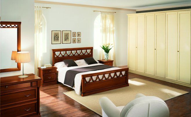 Luminosa camera da letto con letto in legno, comò, toletta e ampio armadio color crema, vicino a finestre soleggiate.