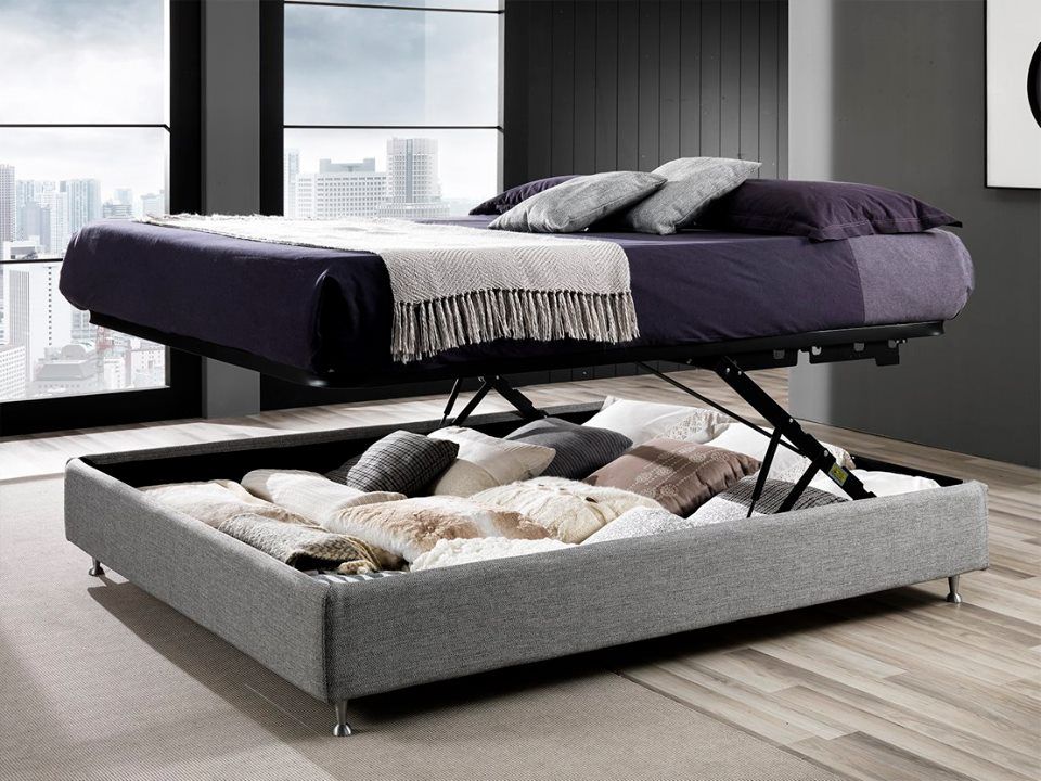 Letto contenitore grigio con apertura a sollevamento in una camera da letto moderna, che mostra il vano portaoggetti nascosto sottostante.