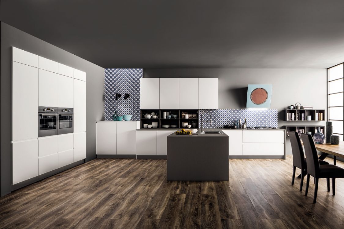 Cucina moderna bianca con pavimento in legno, elettrodomestici a incasso, isola e sedie da pranzo.