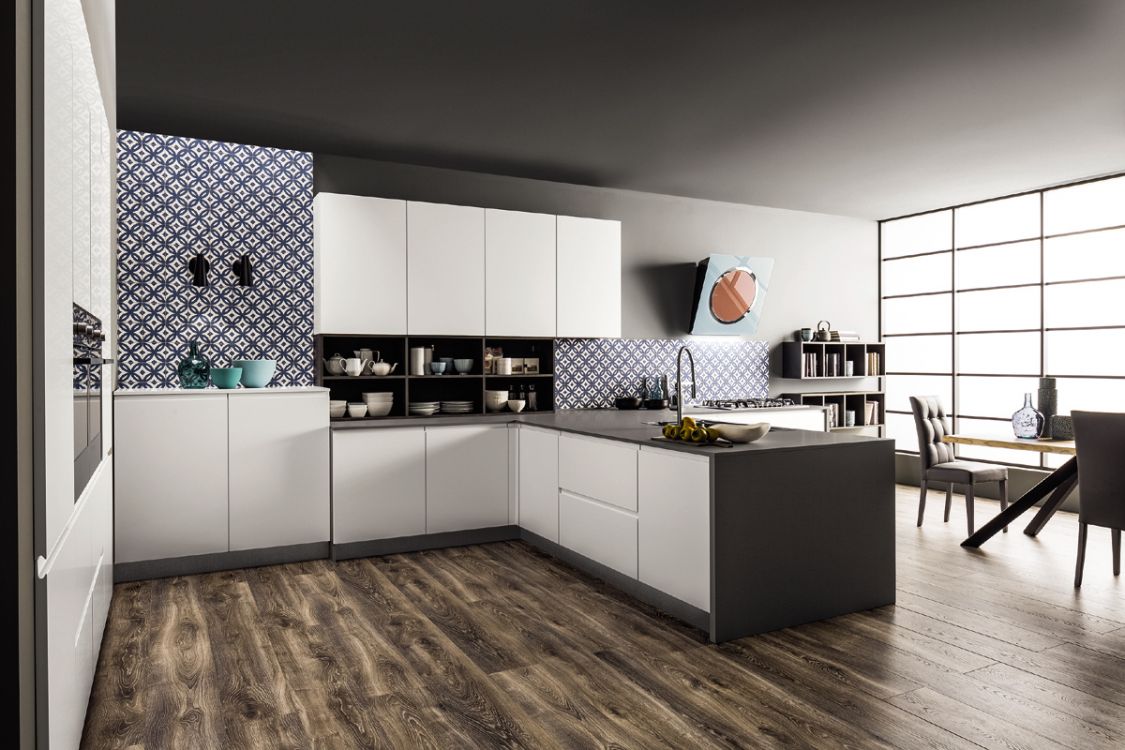 Cucina moderna a pianta aperta con mobili bianchi, pavimento in legno scuro e isola centrale adiacente alla zona pranzo.