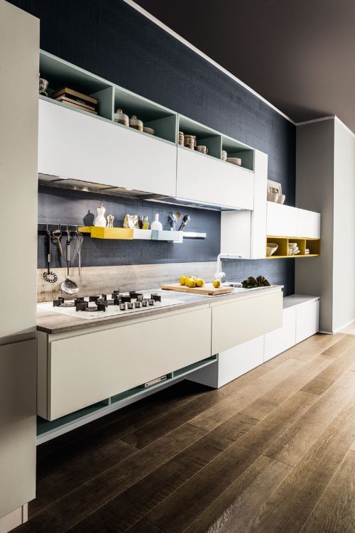 Cucina moderna e minimalista con mobili bianchi, mensole a vista, piano cottura a gas e pavimento in legno.
