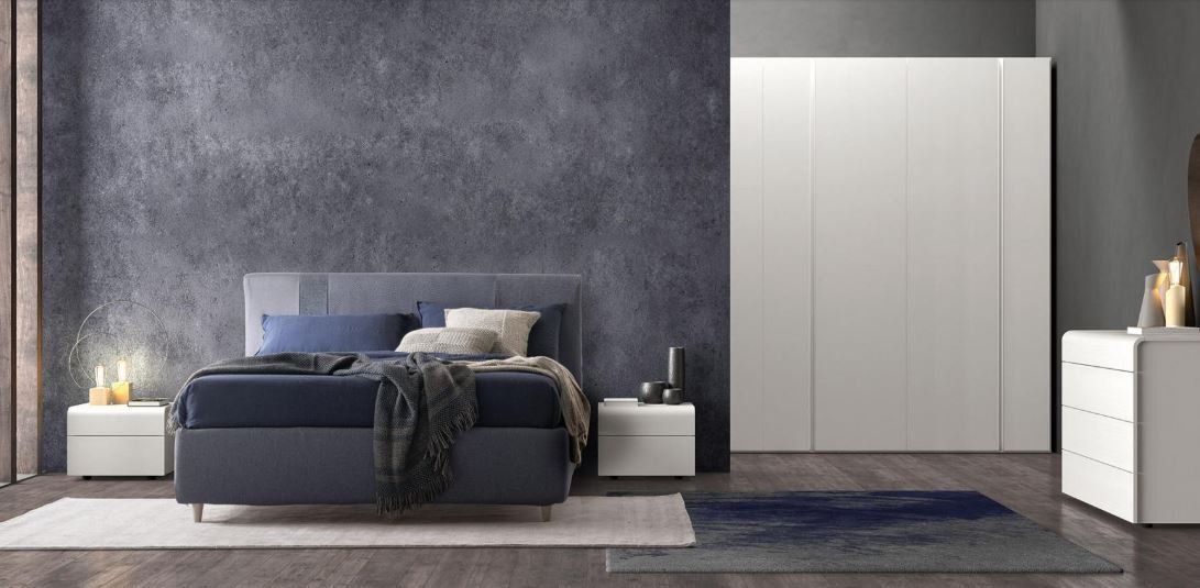 Camera da letto moderna con pareti grigie, letto blu, armadi bianchi e comodini illuminati da luci soffuse.