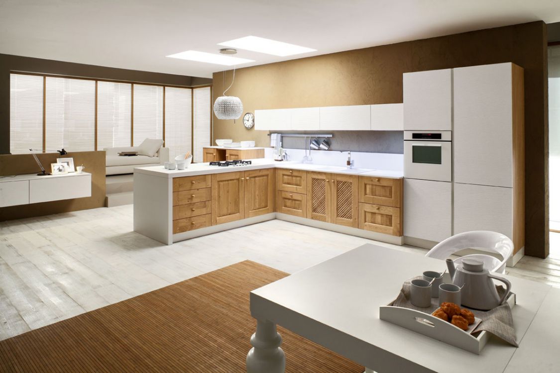 Cucina moderna con mobili in legno chiaro, ripiani bianchi e un tavolo da pranzo in primo piano.