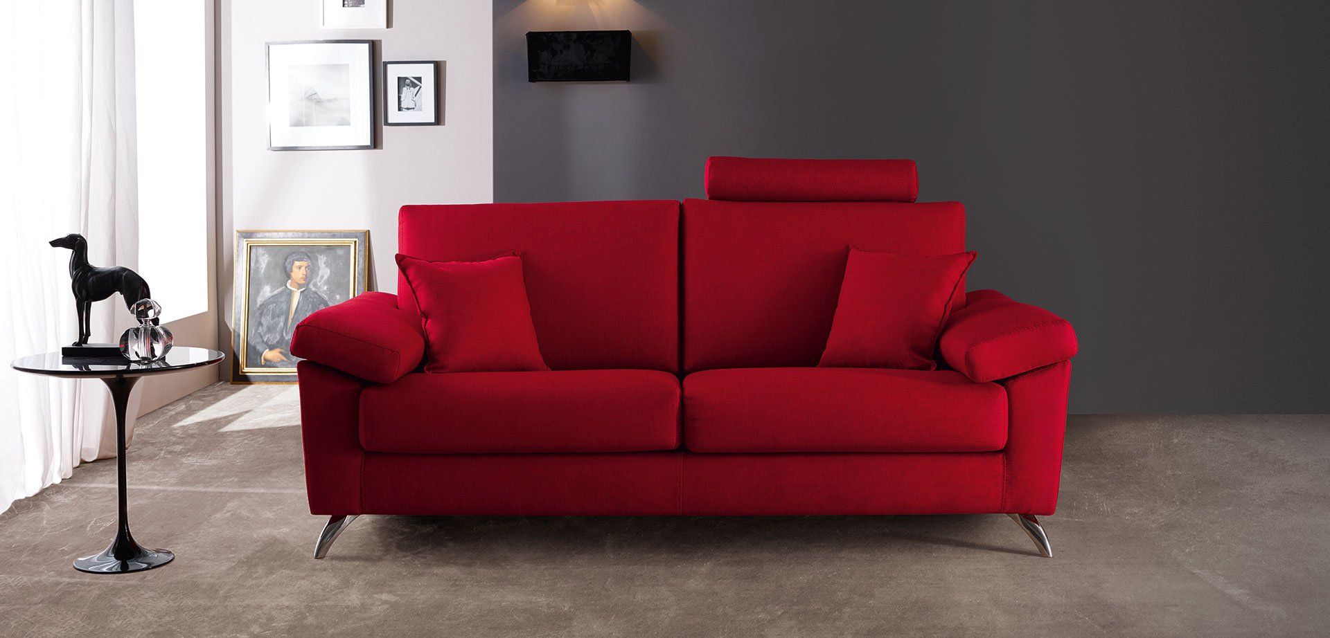 Divano rosso in un soggiorno moderno con parete d'accento scura e tavolino laterale.